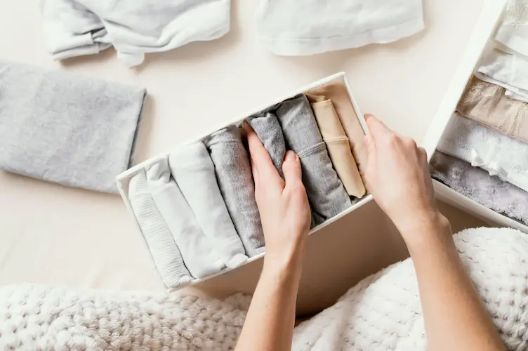 close up organizing folded clothes in box