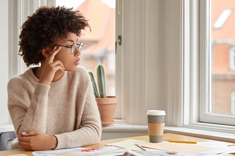 woman thinking at coffee shop looking out window