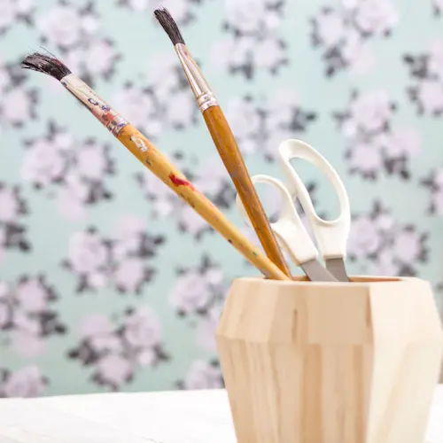 paint brushes and scissors in cup floral background