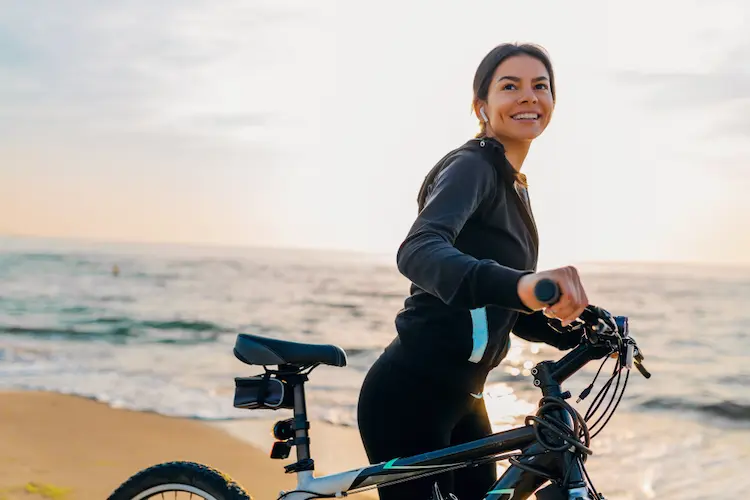 healthy young woman riding bike on beach healthy habits