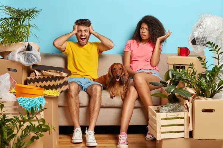 couple on couch with lots of clutter overwhelmed 
ruthless decluttering 
