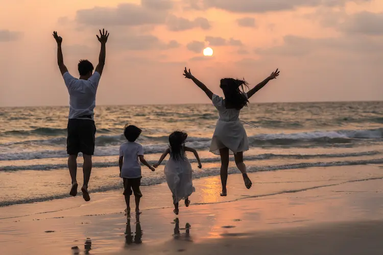 family jumping at beach at sunset