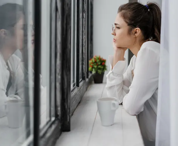 woman at window bar drinking coffee thinking