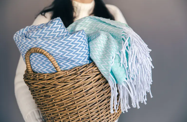 woman holding basket with throw blankets