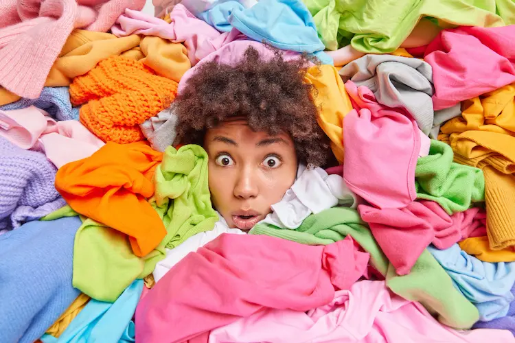 black woman buried in a pile of clothes looking overwhelmed