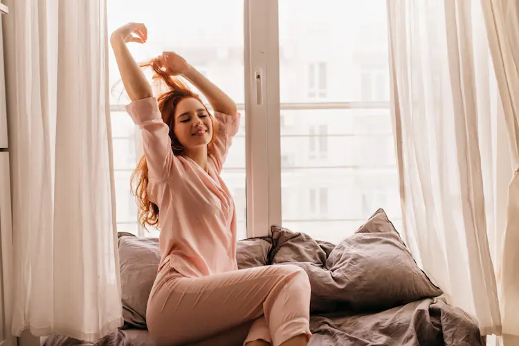 happy woman red hair window and pillows pjs self care