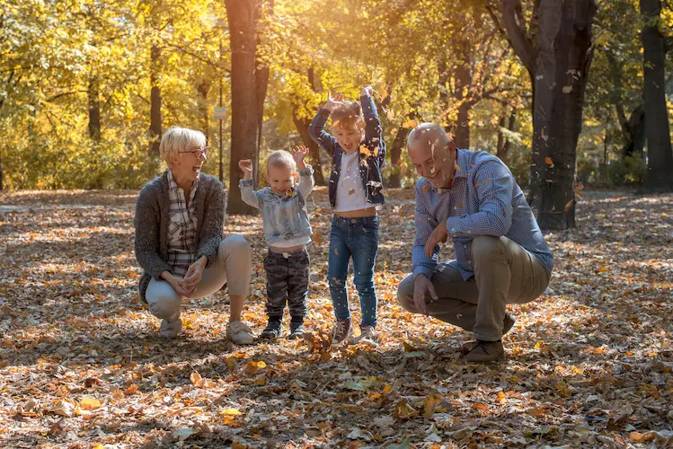 grandchildren grandparents throwing leaves park spending time together 1