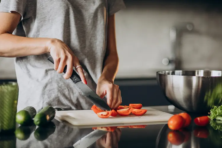 woman cooking slicing tomato