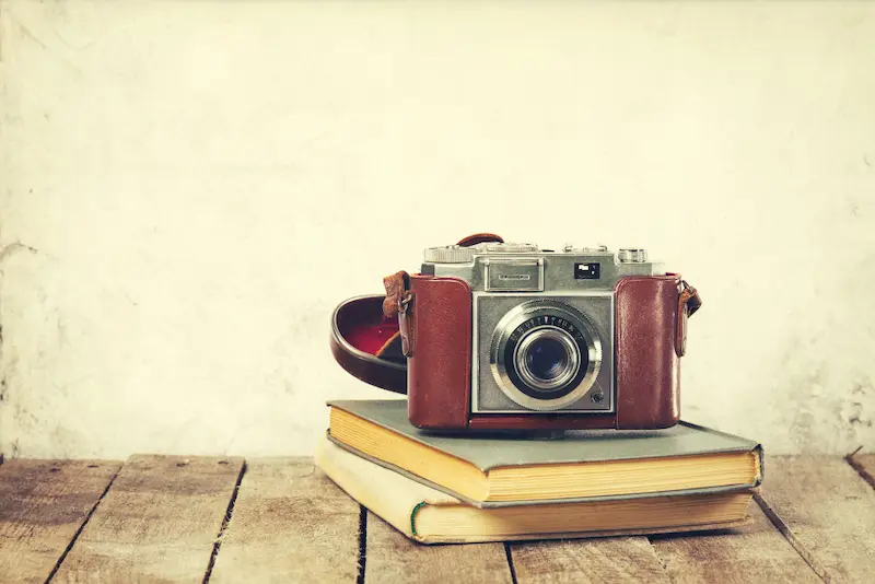 old camera on top of notebooks sepia