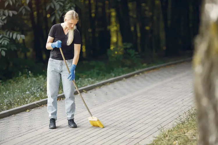 woman sweeping walkway outside