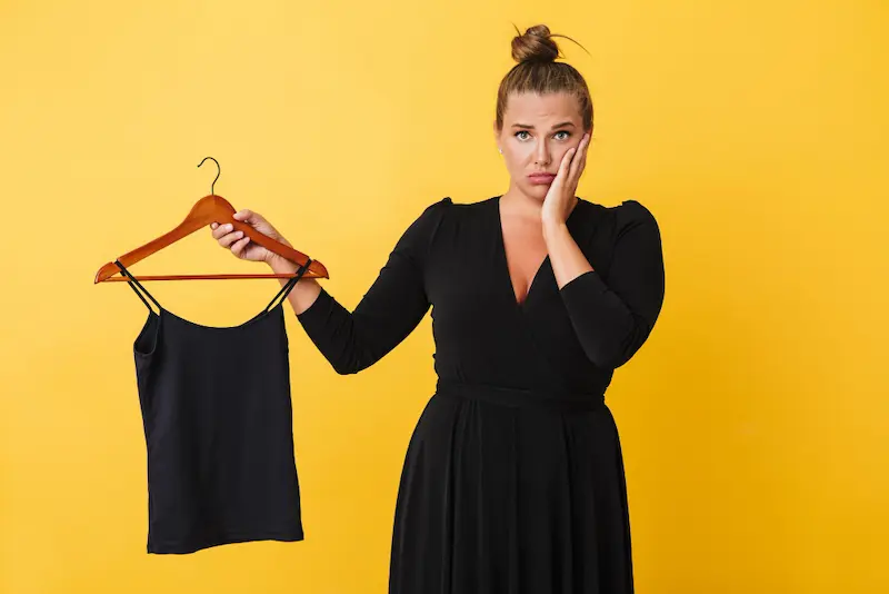 young woman black dress holding too small tank top on hanger

fit clothing