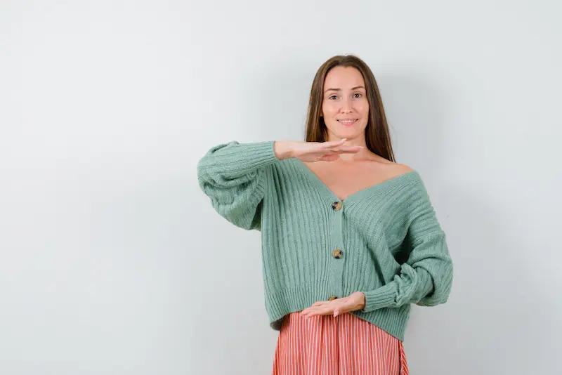 young woman cardigan skirt showing large size sign looking cheerful front view