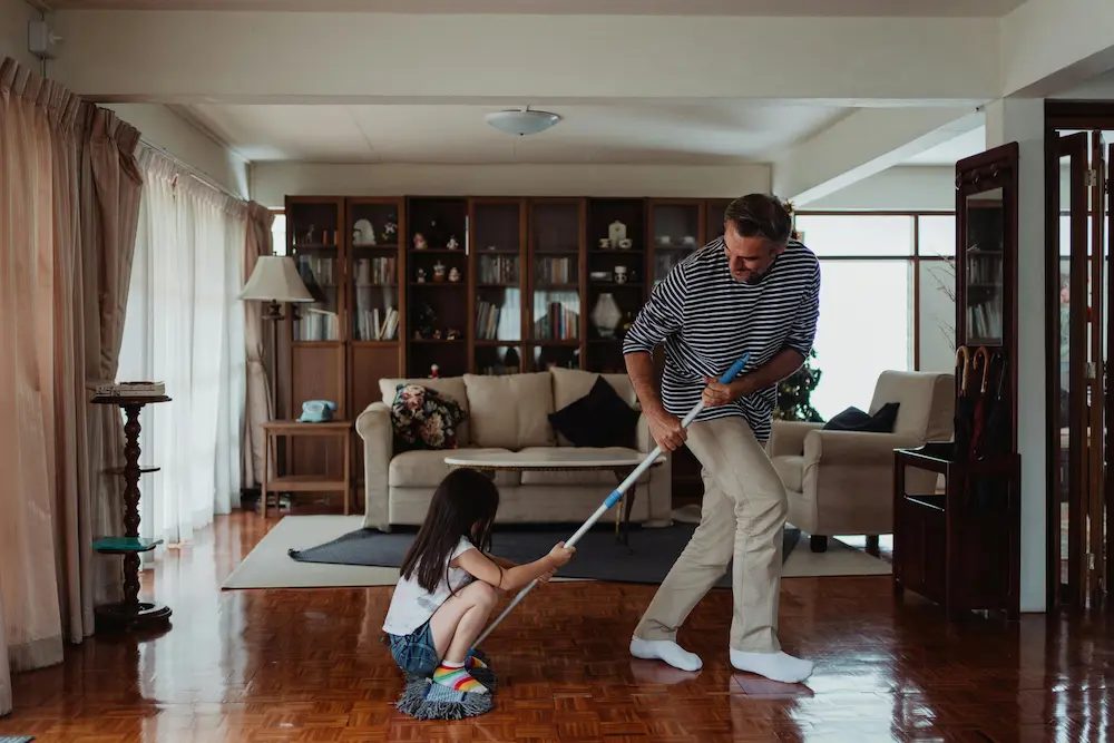 dad and daughter play as he mops the floor